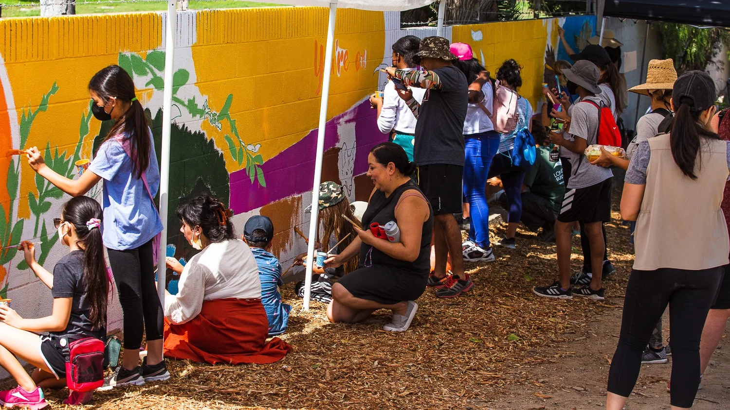 Community members painting a mural on a Long Beach wall